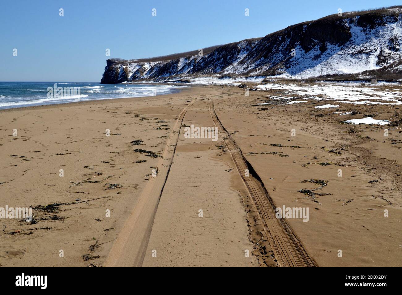 Des marques de pneu sur le sable d'une plage déserte un jour de printemps Banque D'Images