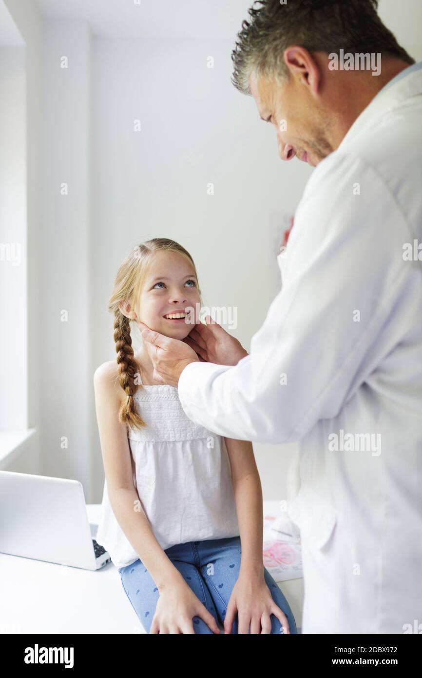 le médecin masculin en manteau blanc examine jeune, jolie fille dans sa  pratique Photo Stock - Alamy
