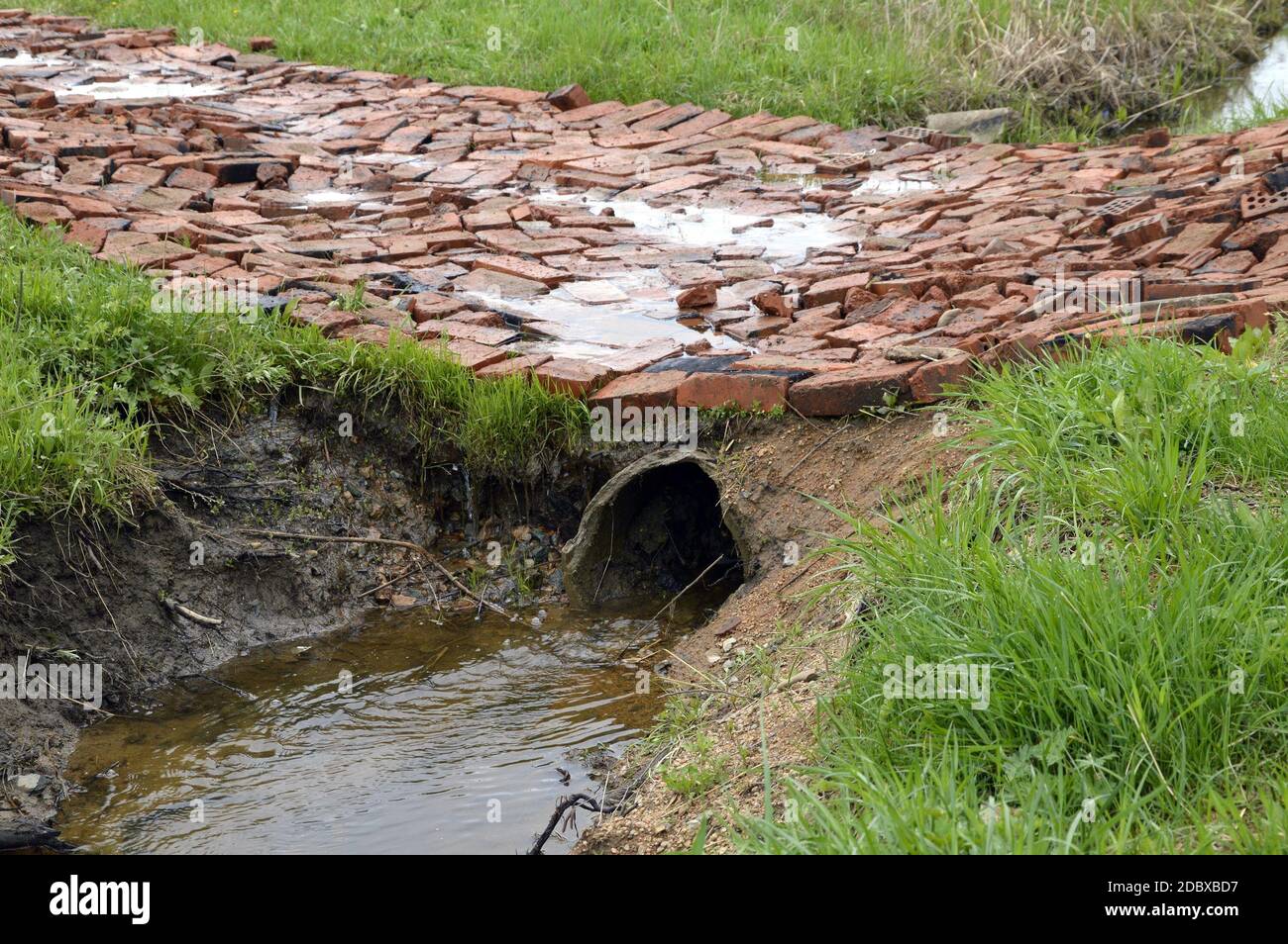 Tuyau de système de drainage pour l'eau de pluie qui coule dans un fossé.  Une promenade en brique à travers elle. Campagne russe Photo Stock - Alamy