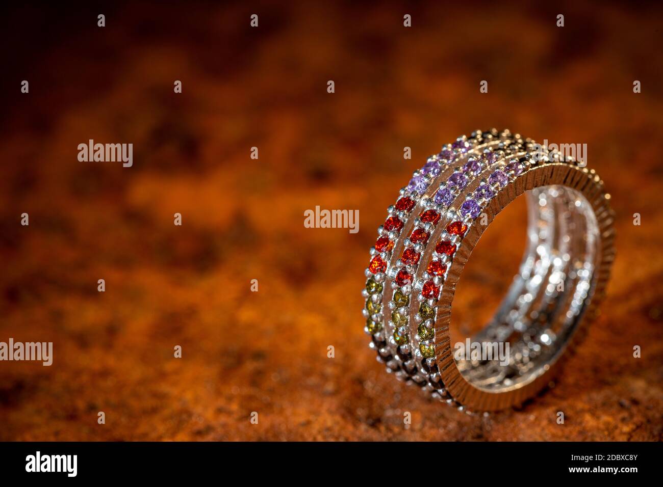 Bague argentée de style moderne avec petits cristaux colorés sur le brun arrière-plan Banque D'Images