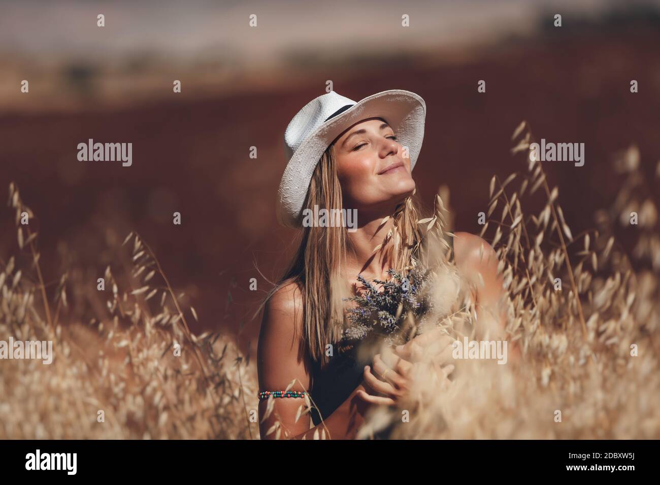 Portrait d'une jeune femme blonde heureuse à l'extérieur. Bouquet de fleurs de lavande pour fille. Se tenir dans un champ de blé. Profiter de la nature. Magnifique Sunny Day Banque D'Images