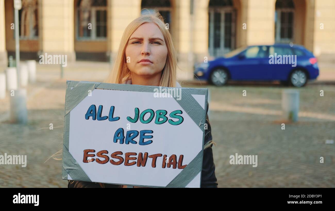 En mars, une femme a attiré l'attention sur l'importance de tous les types d'emplois. Elle tient la bannière et marche dans la rue. Banque D'Images