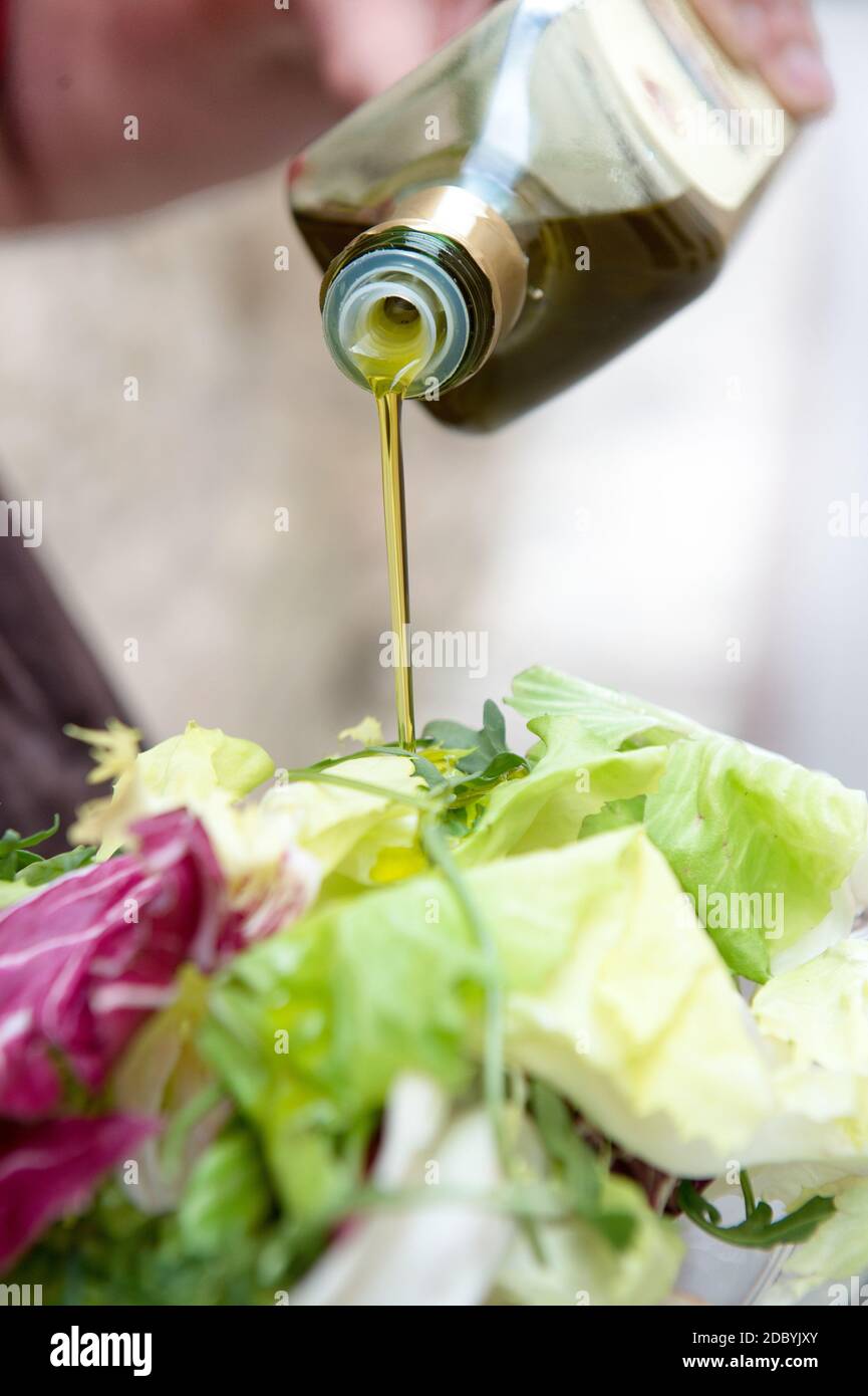 vinaigrette avec un filet d'huile d'olive extra vierge italienne d'une salade verte fraîche mélangée Banque D'Images