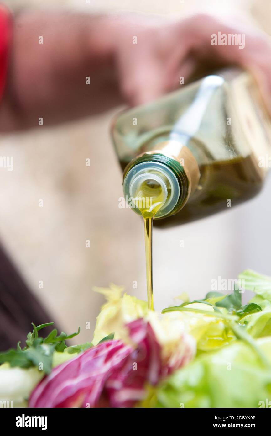 vinaigrette avec un filet d'huile d'olive extra vierge italienne d'une salade verte fraîche mélangée Banque D'Images