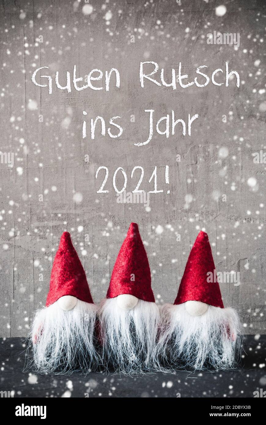 Trois gnomes gris avec texte anglais Guten Rutsch ins Jahr 2021 signifie bonne année et chapeau de sac de gelée rouge. Fond de ciment urbain avec flocons de neige. Ven Banque D'Images