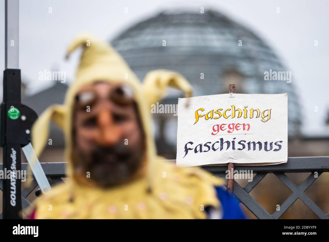 Berlin, Allemagne. 18 novembre 2020. Un homme déguisé en imbécile avec un panneau disant 'Fasching gegen Faschismus' (Carnaval contre le fascisme) se trouve devant le bâtiment du Reichstag sur le Marschallbrücke lors d'une manifestation contre les restrictions de la couronne du gouvernement allemand. Dans le même temps, la nouvelle version de la loi sur la protection contre les infections doit être adoptée par le Bundestag et le Bundesrat dans une procédure rapide. Credit: Christoph Soeder/dpa/Alay Live News Banque D'Images