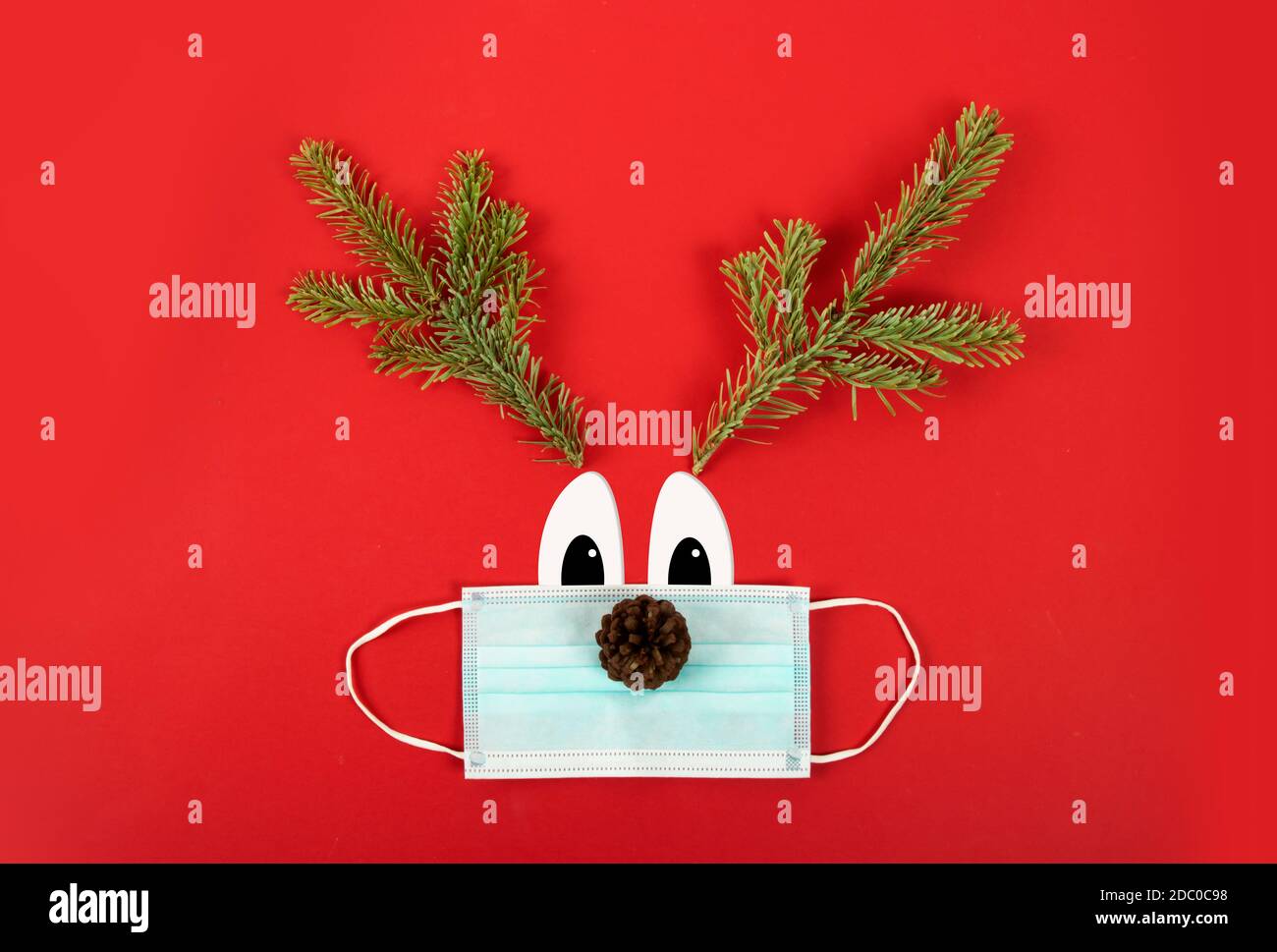 Fêtes de Noël pendant la pandémie de Covid-19. Masque chirurgical avec branches de sapin représentant un cerf. Banque D'Images