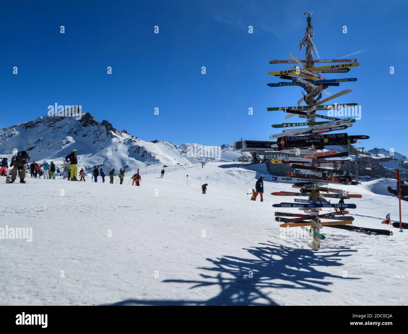 Pardatschgrat, panneau de croisement avec skis pointant vers les villes et les skieurs internationaux, station de ski d'Ischgl-Samnaun, Autriche Banque D'Images