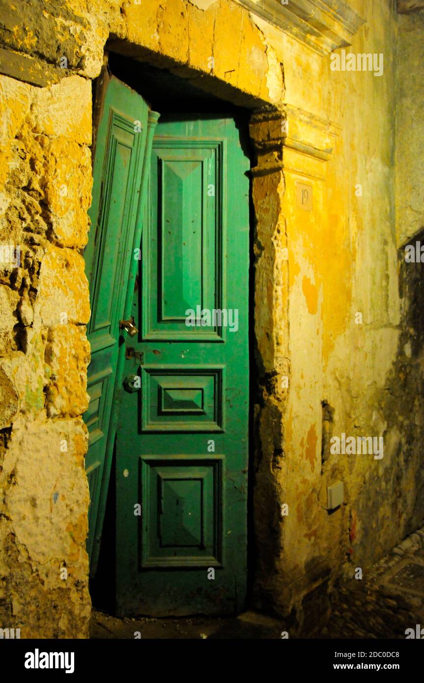 Vert, vieux et or: emerald porte en bois cassée d'une vieille maison avec des murs jaune-or à Rhodes, Grèce Banque D'Images