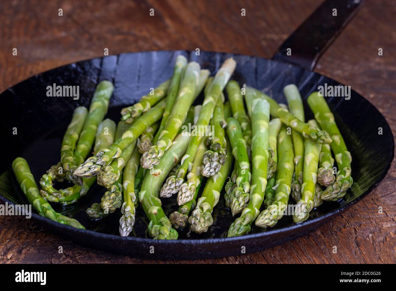 asperges vertes fraîches dans une poêle sur bois sombre Banque D'Images