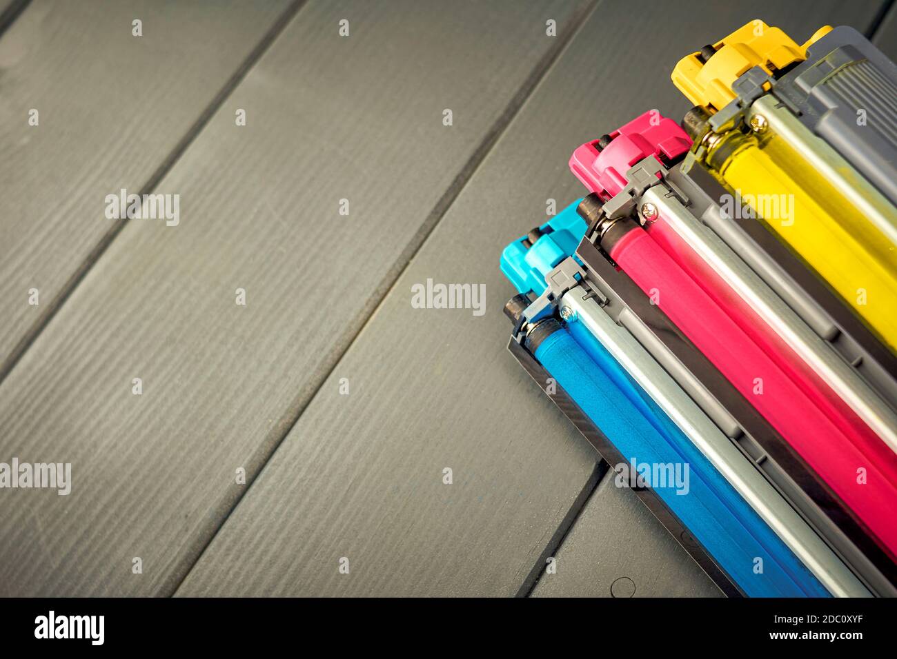 Cartuchos de toner amarillo, cyan y magenta para sustitución en una impresora de color sobre fondo de madera Banque D'Images