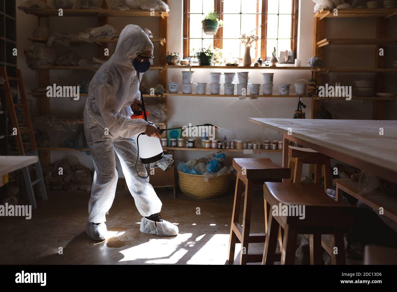 Nettoyant mâle caucasien dans les vêtements de protection travaillant dans le studio de poterie Banque D'Images