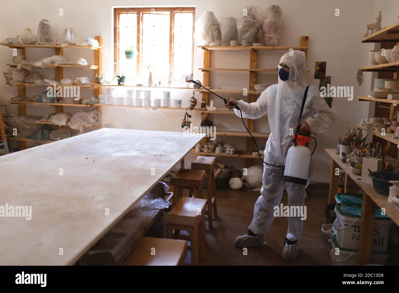 Nettoyant mâle caucasien dans les vêtements de protection travaillant dans le studio de poterie Banque D'Images