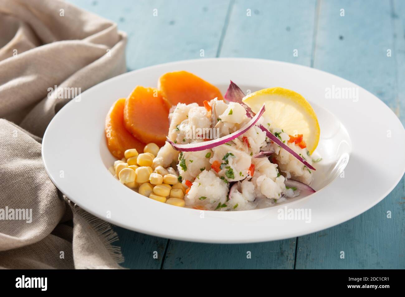 Ceviche péruvienne traditionnelle avec poisson, patate douce, maïs et légumes sur table en bois bleu Banque D'Images