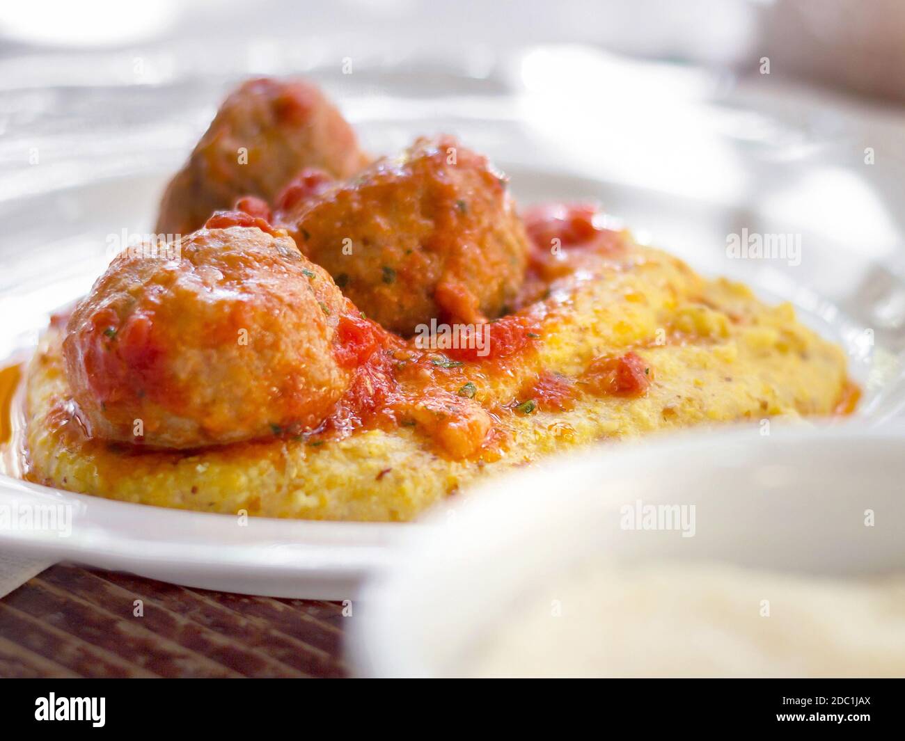 Polenta avec boulettes de viande dans la sauce tomate. Boulettes de viande de porc et de bœuf italiennes traditionnelles servies sur de la polenta avec une sauce tomate, du basilic, du parmesan et un filet d'argoule Banque D'Images