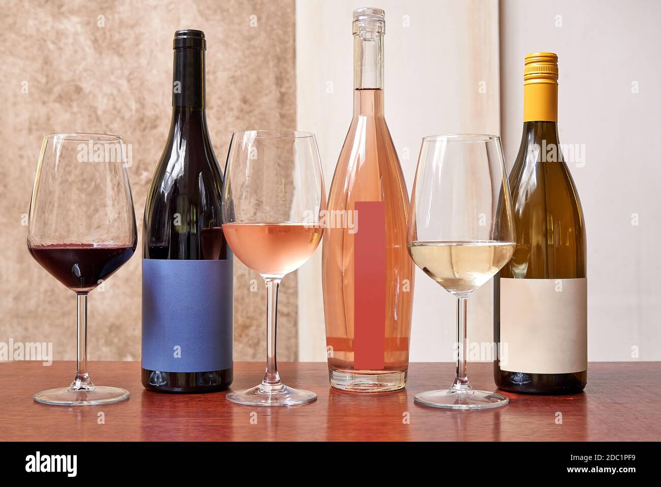 Trois types différents de bouteilles de vin et trois verres sur fond texturé Banque D'Images