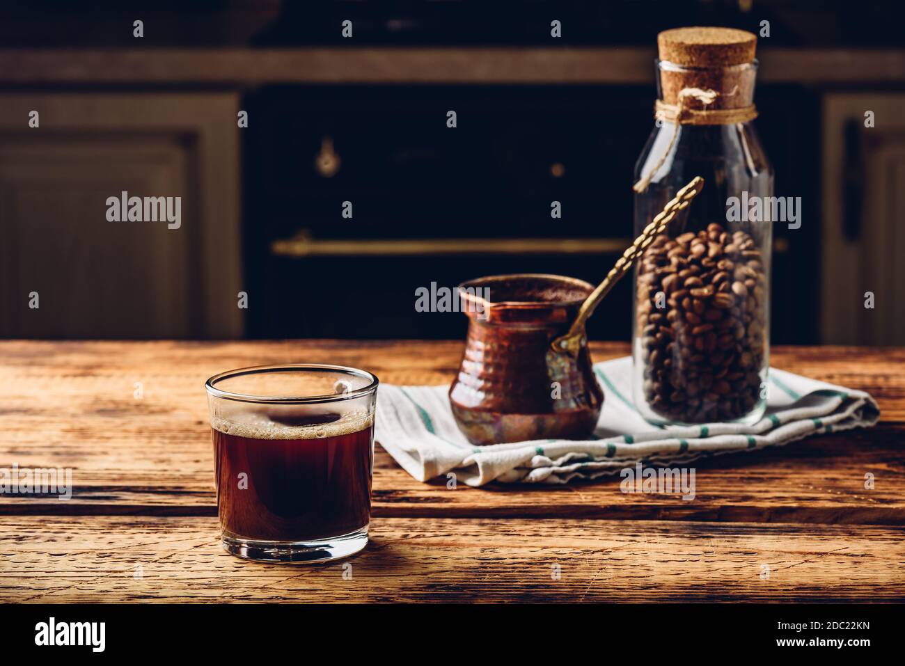 Café turc fraîchement préparé dans un verre à boire. Cezve et pot de grains de café rôtis. Banque D'Images