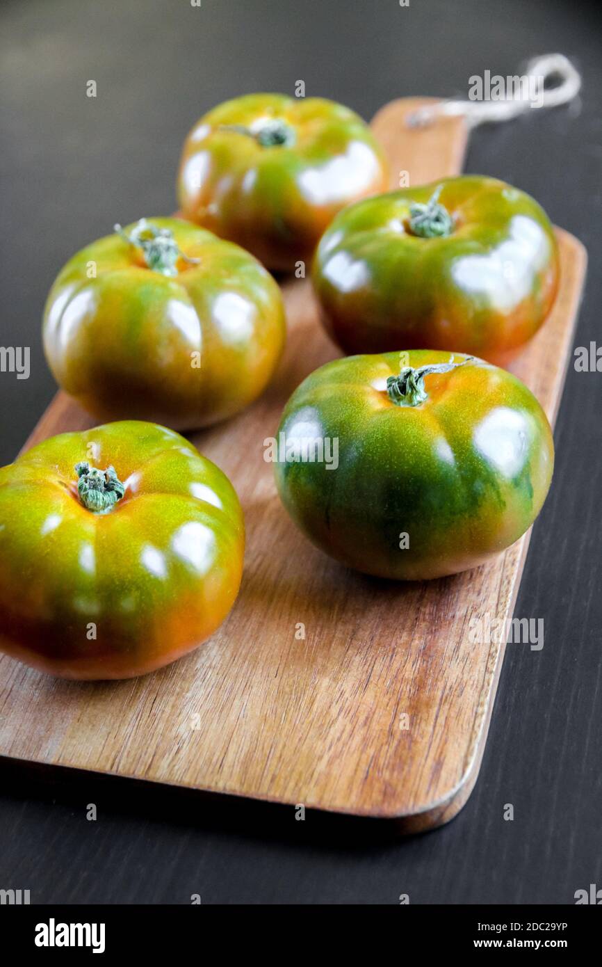 Tomates biologiques en jante noire sur une planche à découper en bois Banque D'Images