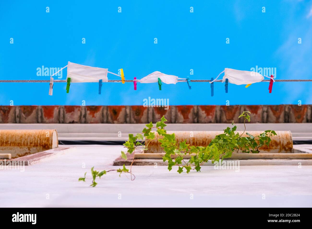 Masques faciaux suspendus d'une corde à linge séchant au soleil, à Setúbal, Portugal. Banque D'Images