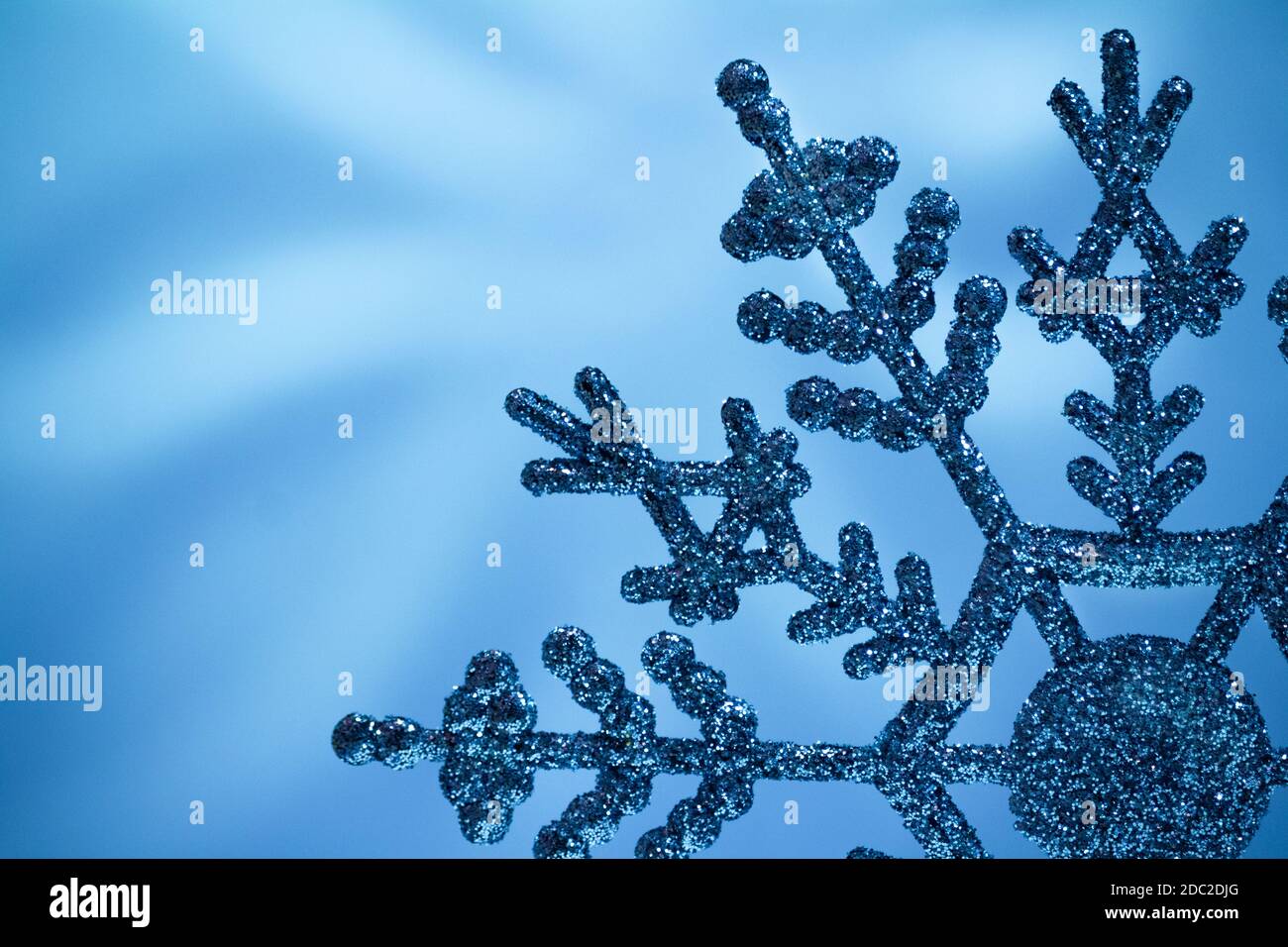 Macro flocon de neige brillant sur fond bleu flou. Carte de joyeux Noël. Copier l'espace Banque D'Images