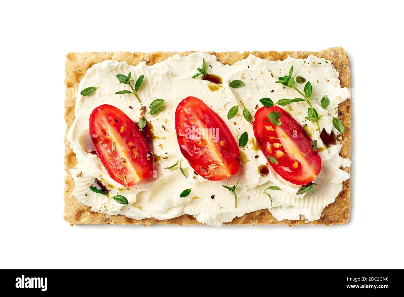 Pain croustillant avec fromage à la crème, tranches de tomate et herbes sur blanc Banque D'Images