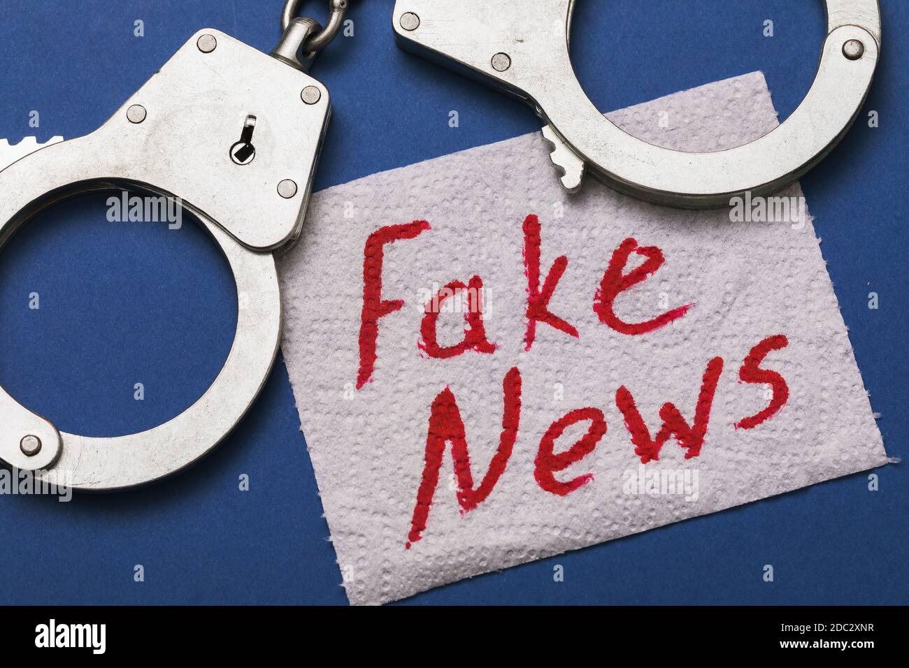 Menottes et une feuille de papier toilette avec l'inscription. Concept sur le thème de la punition pour les fausses nouvelles. Banque D'Images