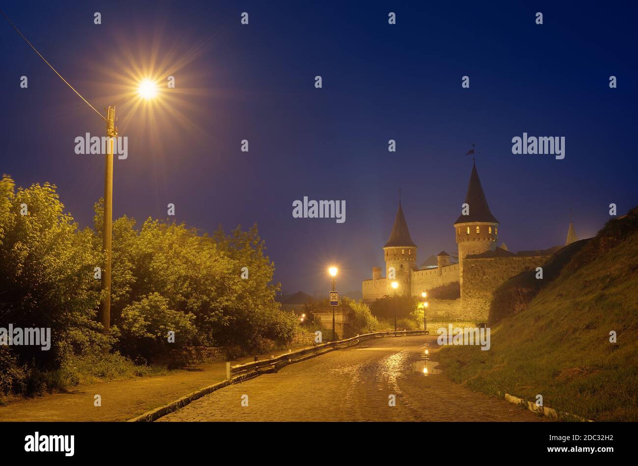 Paysage de nuit avec une route menant à l'ancienne forteresse. Feu dans la rue. Site historique. Vieille ville de Kamenetz-Podolsk, Ukraine, Europe Banque D'Images