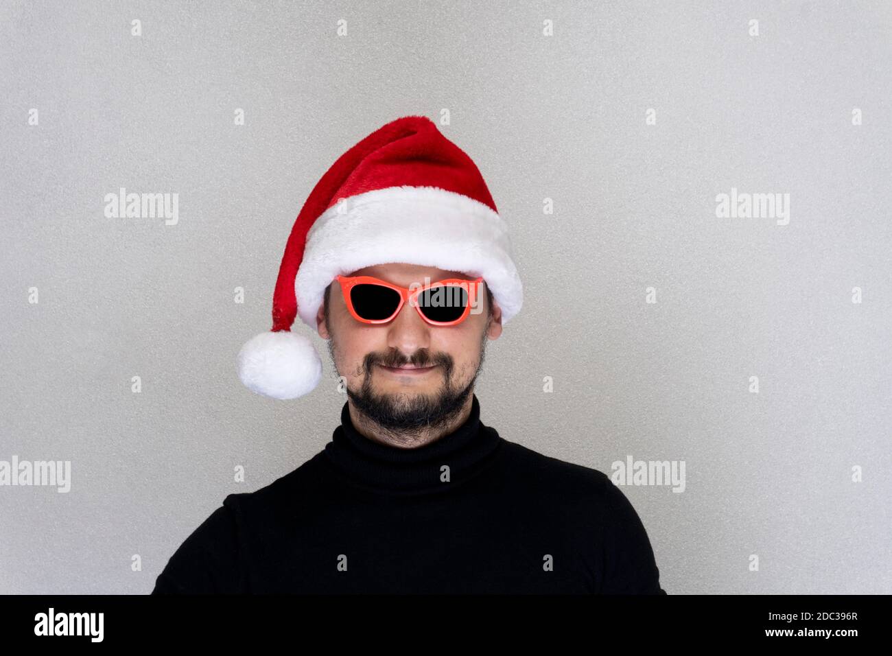 Chapeau de père Noël rouge barbu avec lunettes de soleil rouges. Banque D'Images