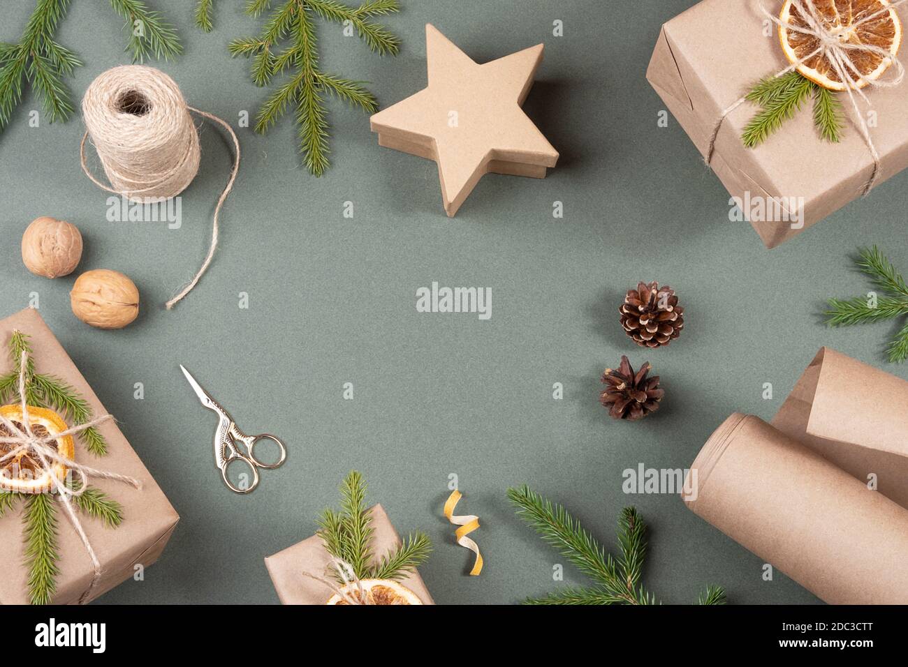Cadre, bordure faite de boîtes, papier artisanal, ficelle, ciseaux, oranges séchées et décor naturel pour l'emballage DE NOËL, cadeaux du nouvel an sur fond vert. Co Banque D'Images