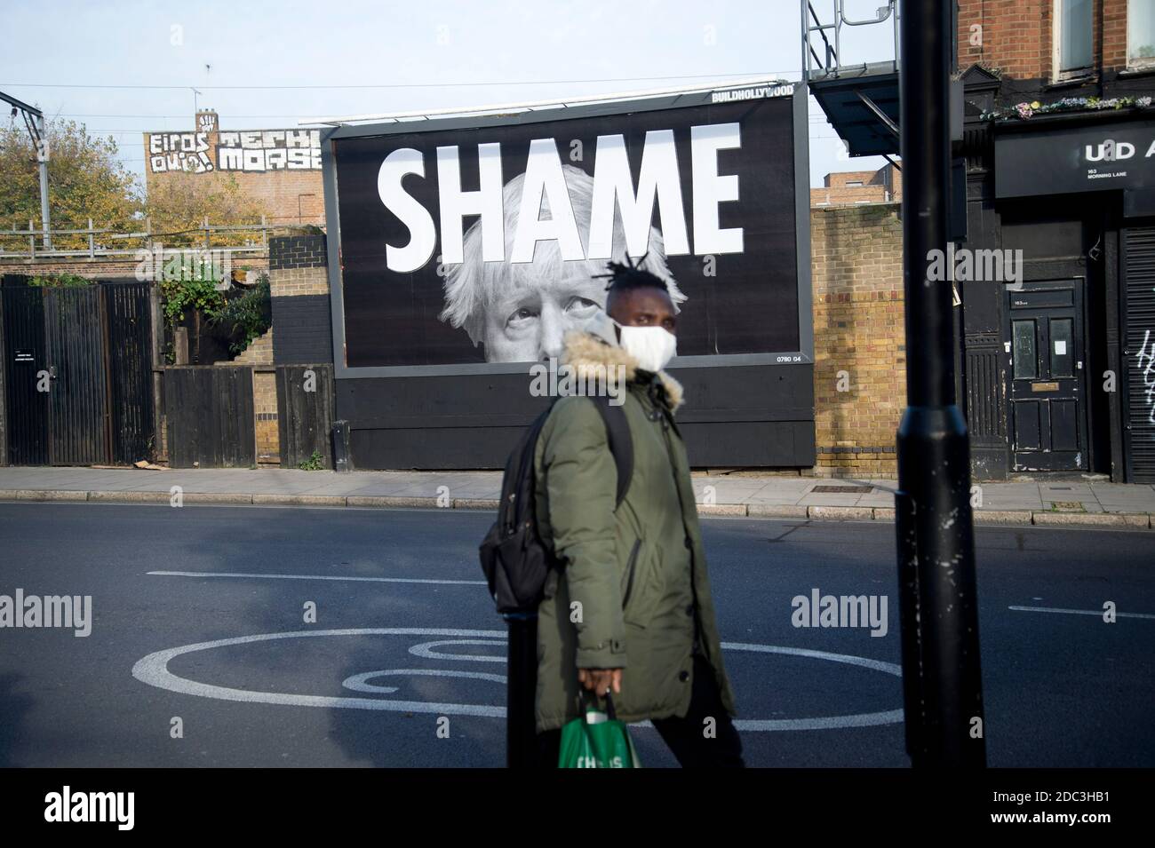 Morning Lane, Hackney, Londres, le 2020 novembre lors de la pandémie de Covid-19 (coronavirus). Verrouillage 2. Un homme noir portant un masque passe devant une affiche Banque D'Images