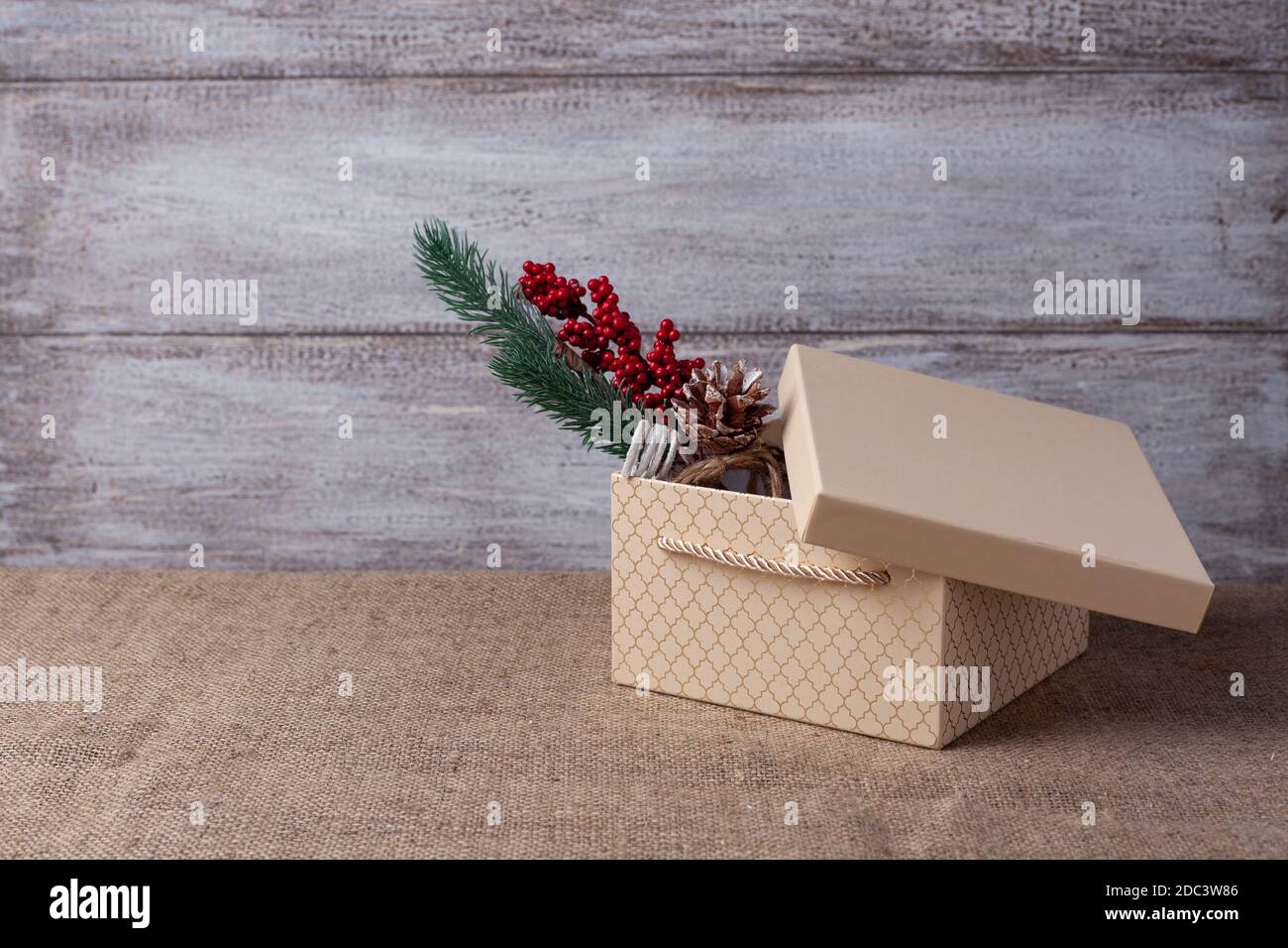 maquette de boîte cadeau beige avec couvercle ouvert et Branche d'un sapin de Noël avec décorations à l'intérieur un fond en bois Banque D'Images