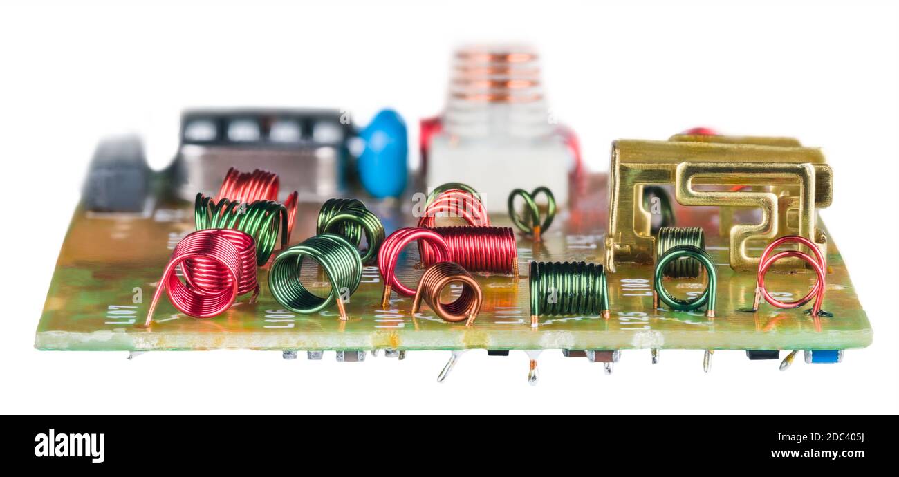 Enroulement de fil de couleur des bobines de noyau d'air dans la carte de  circuit imprimé sur fond blanc. Diverses inductances RF rouges ou vertes  pour la réception haute fréquence. Vue latérale