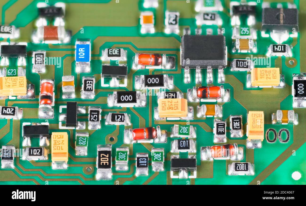 Gros plan des composants électroniques à semi-conducteurs. Carte de circuit imprimé verte. Technologie de montage en surface de résistances, transistors, diodes ou condensateurs. Banque D'Images