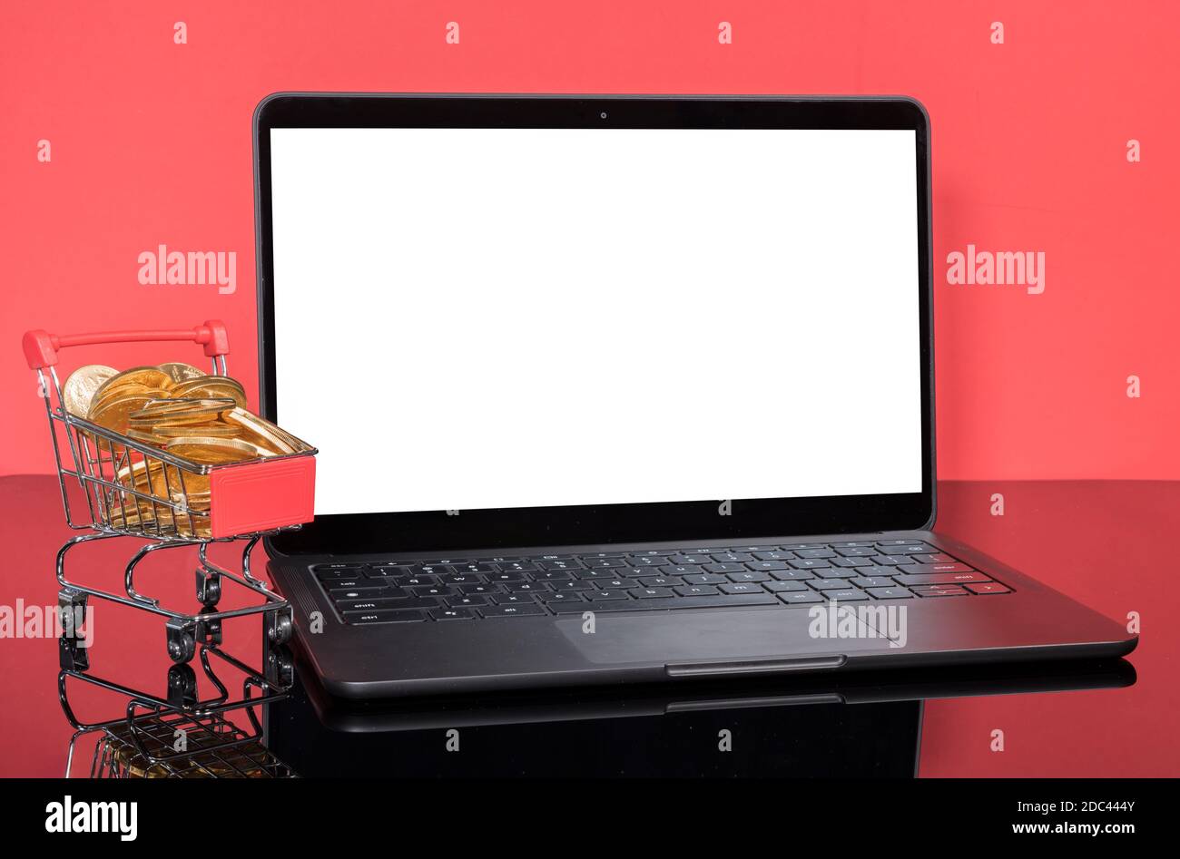 Concept pour les ventes en ligne et d'hiver avec panier rempli pièces de monnaie en or devant un ordinateur portable moderne avec écran isolé Banque D'Images