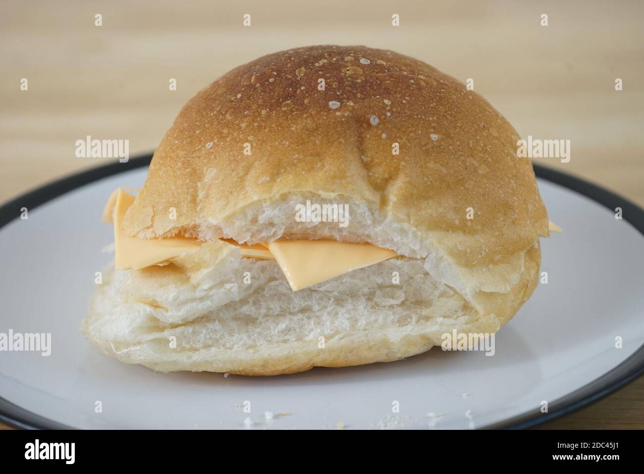Un rouleau de fromage ordinaire à l'aspect solitaire sur une assiette Banque D'Images