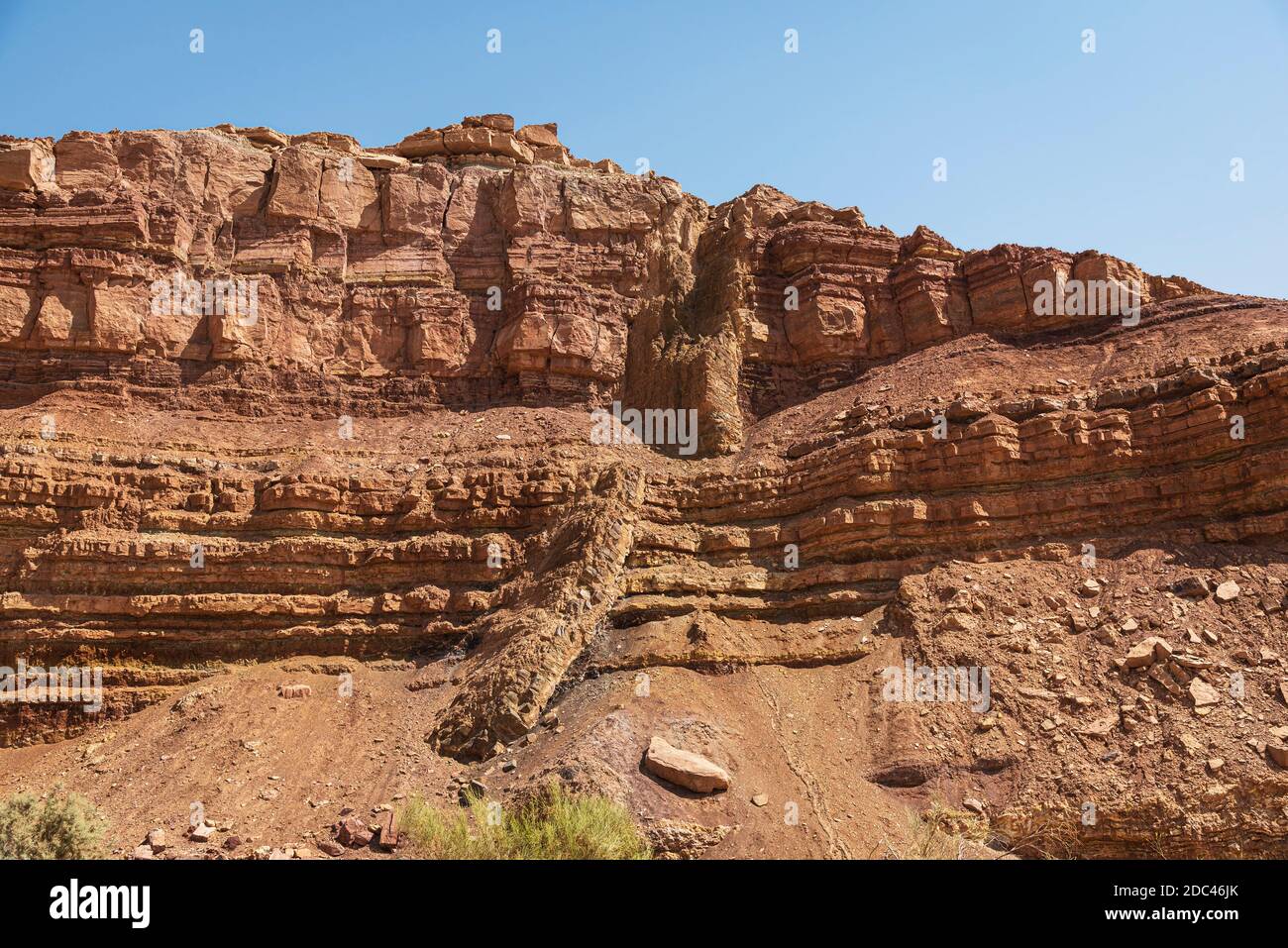 une digue ignée magmatique diagonale traverse le rouge et l'orange Couches horizontales de calcaire dans nahal Ardon dans le Makhtesh Ramon cratère en Israël Banque D'Images