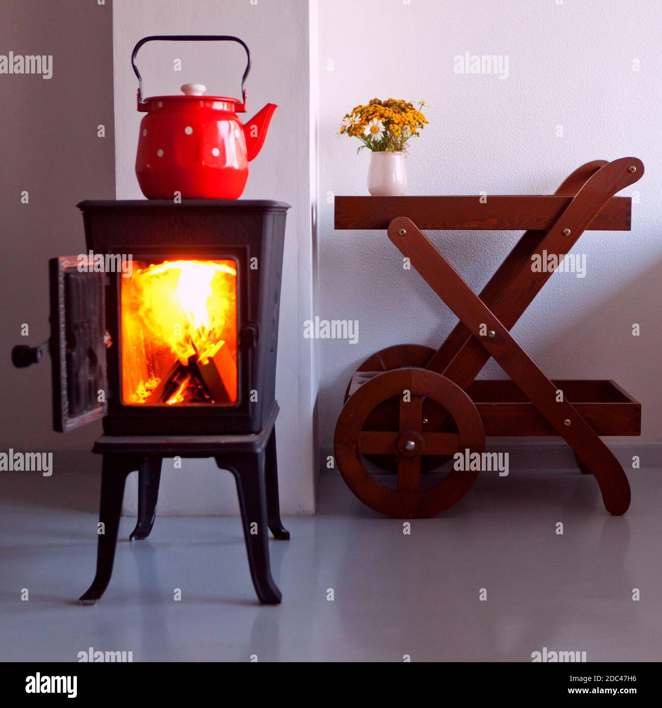 maison de campagne et intérieur avec four. bouilloire rouge bouillant sur un poêle rétro dans la cuisine. cheminée. Mise au point sur un bec Banque D'Images