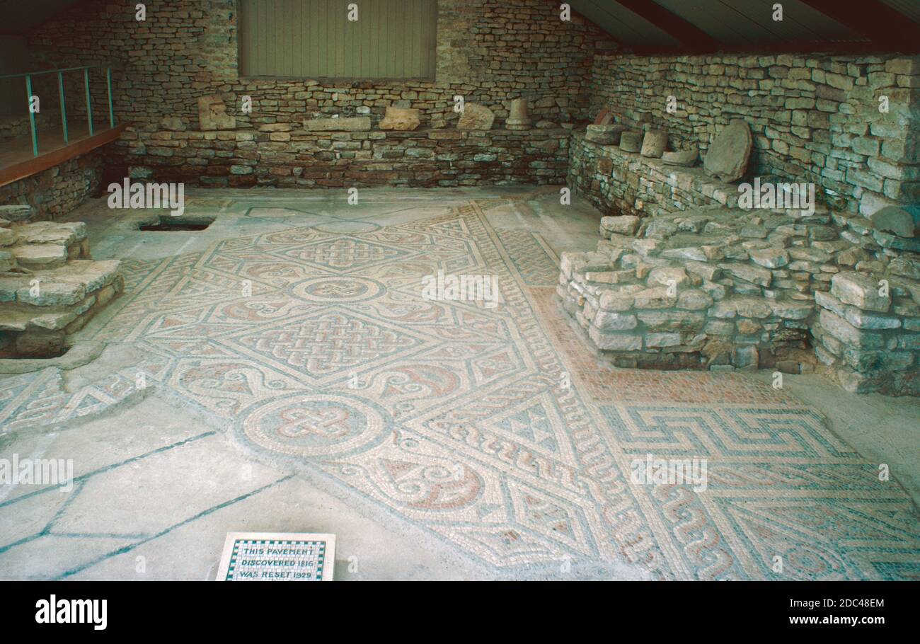 North Leigh Villa - ruines romaines - fouilles archéologiques, juillet 1977. Les vestiges de la villa romaine de North Leigh se trouvent dans un paysage paisible sur les rives de l'Evenlode dans l'Oxfordshire. Cette « villa de cour » est considérée comme l'une des plus grandes villas de Grande-Bretagne romaine. Il était à son plus grand au début du 4ème siècle, inclus: 4 salles de bains, 16 sols en mosaïque et 11 chambres avec chauffage au sol. Aujourd'hui, la disposition rectangulaire de la villa est visible avec un sol en mosaïque presque complet datant du 3ème siècle. Site du patrimoine anglais. Numérisé à partir de diapositives. Banque D'Images