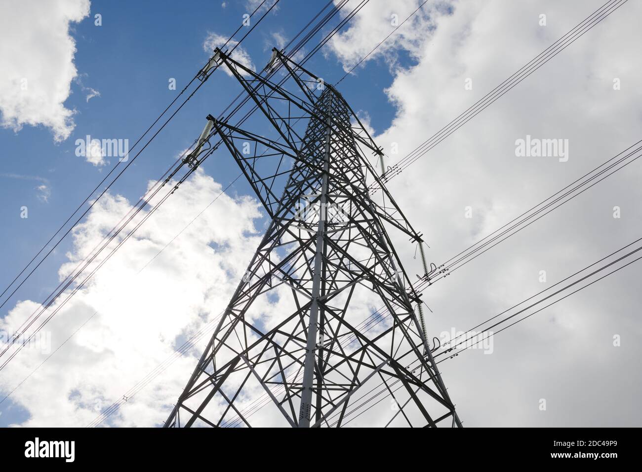 Image à angle bas d'une tour de réseau de transmission électrique. Lignes haute tension silhouetées contre le ciel de l'été. Les entretoises pendent de la tour Banque D'Images