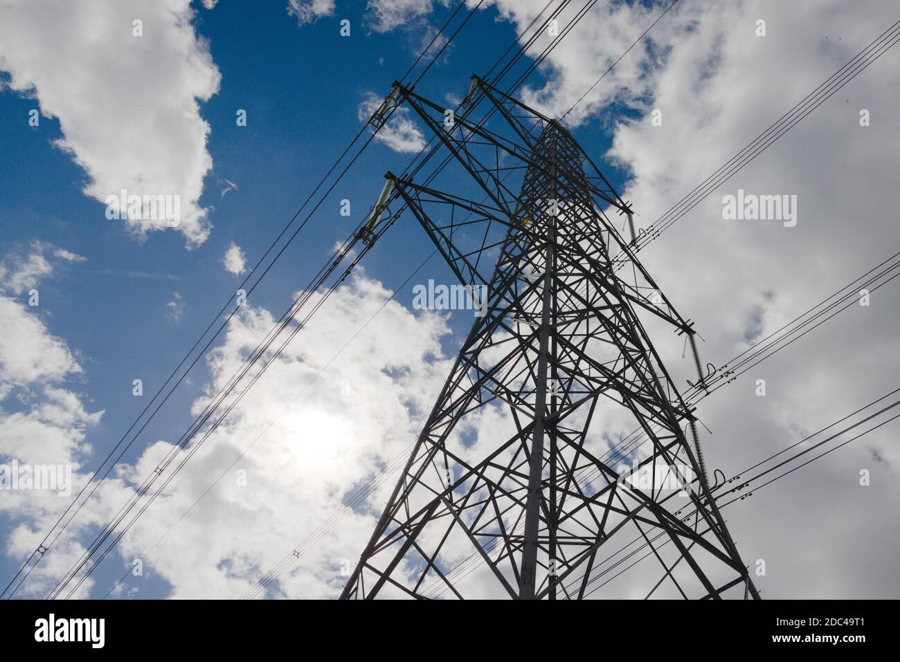 Contrastes environnementaux, grand pylône électrique en métal foncé contre un ciel bleu ciel nuageux naturel. Copiez l'espace vers le côté gauche, en plein soleil Banque D'Images