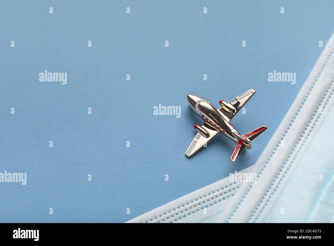 Concept, avion doré volant à travers le ciel bleu et masque médical de l'infection du coronavirus covid-19. Pose à plat avec place pour le texte. Banque D'Images