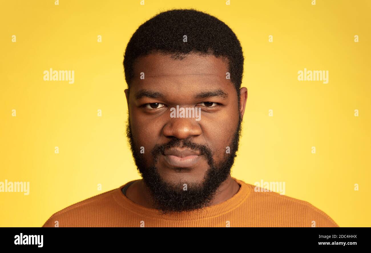 Calme, attentionné. Portrait du jeune homme afro-américain isolé sur fond jaune studio, expression faciale. Magnifique modèle masculin, monochrome, espace de copie. Concept d'émotions humaines, ventes, publicité. Banque D'Images