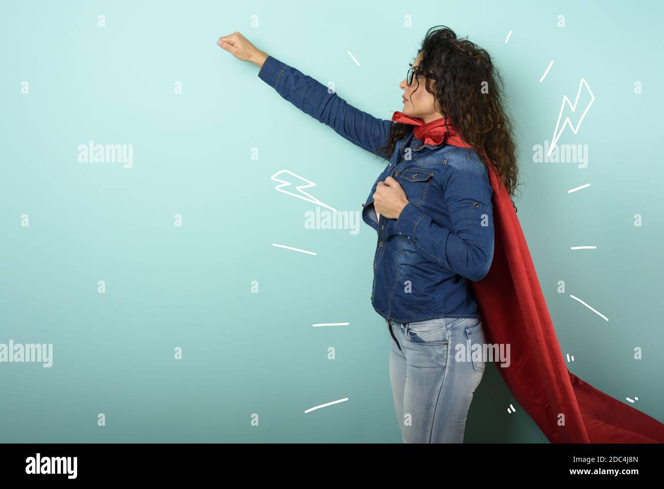 La femme agit comme un super-héros. Concept de détermination et de pouvoir. Fond cyan Banque D'Images