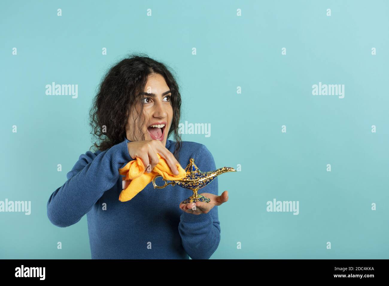 La femme est heureuse de voir qu'elle fonde la lampe d'aladdin. Fond cyan Banque D'Images