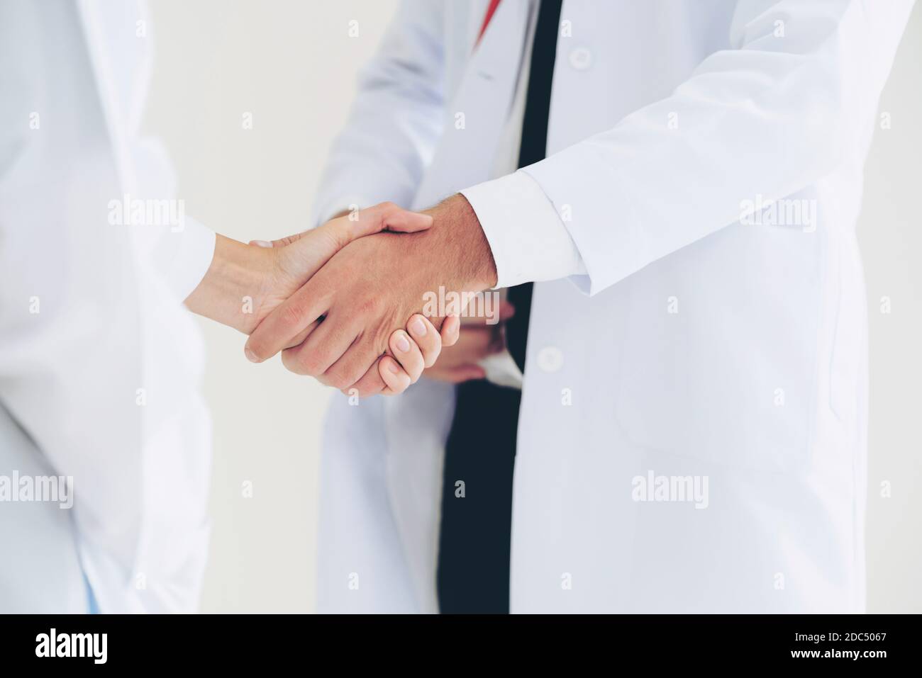 Médecin sur fond blanc donnant la poignée de main à un autre médecin montrant le succès et le travail d'équipe des professionnels de la santé. Gros plan sur les médecins Banque D'Images