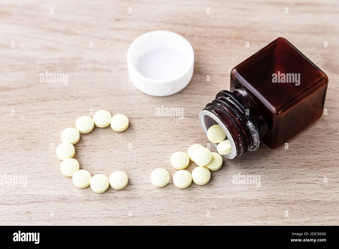 Comprimés jaunes de vitamine C et bouteille sur fond de bois Banque D'Images