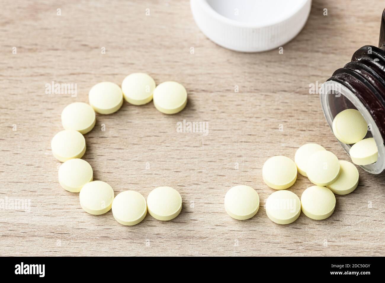 Comprimés jaunes de vitamine C et bouteille sur fond de bois Banque D'Images