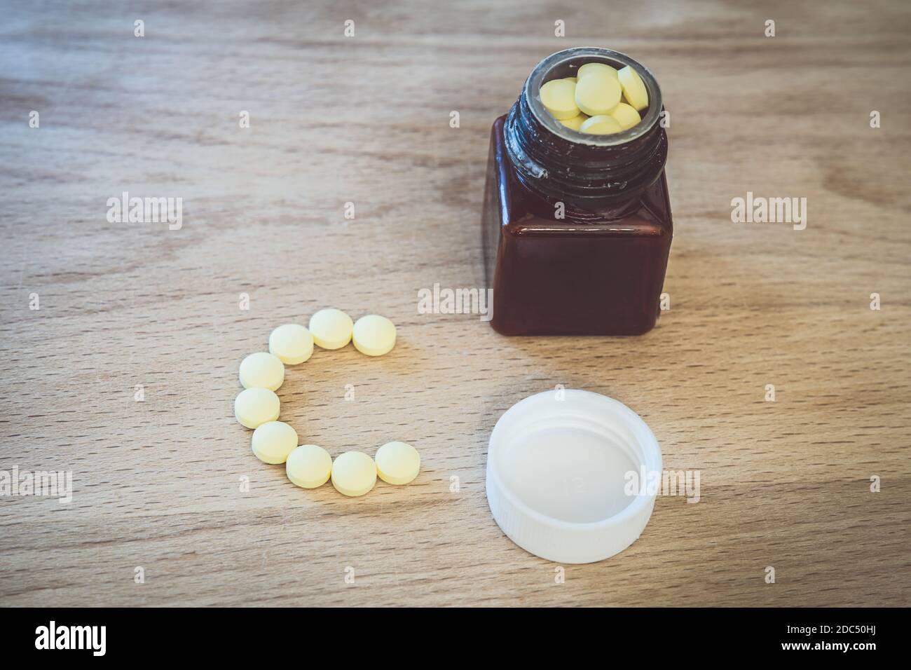 Comprimés jaunes de vitamine C et bouteille sur fond de bois Banque D'Images