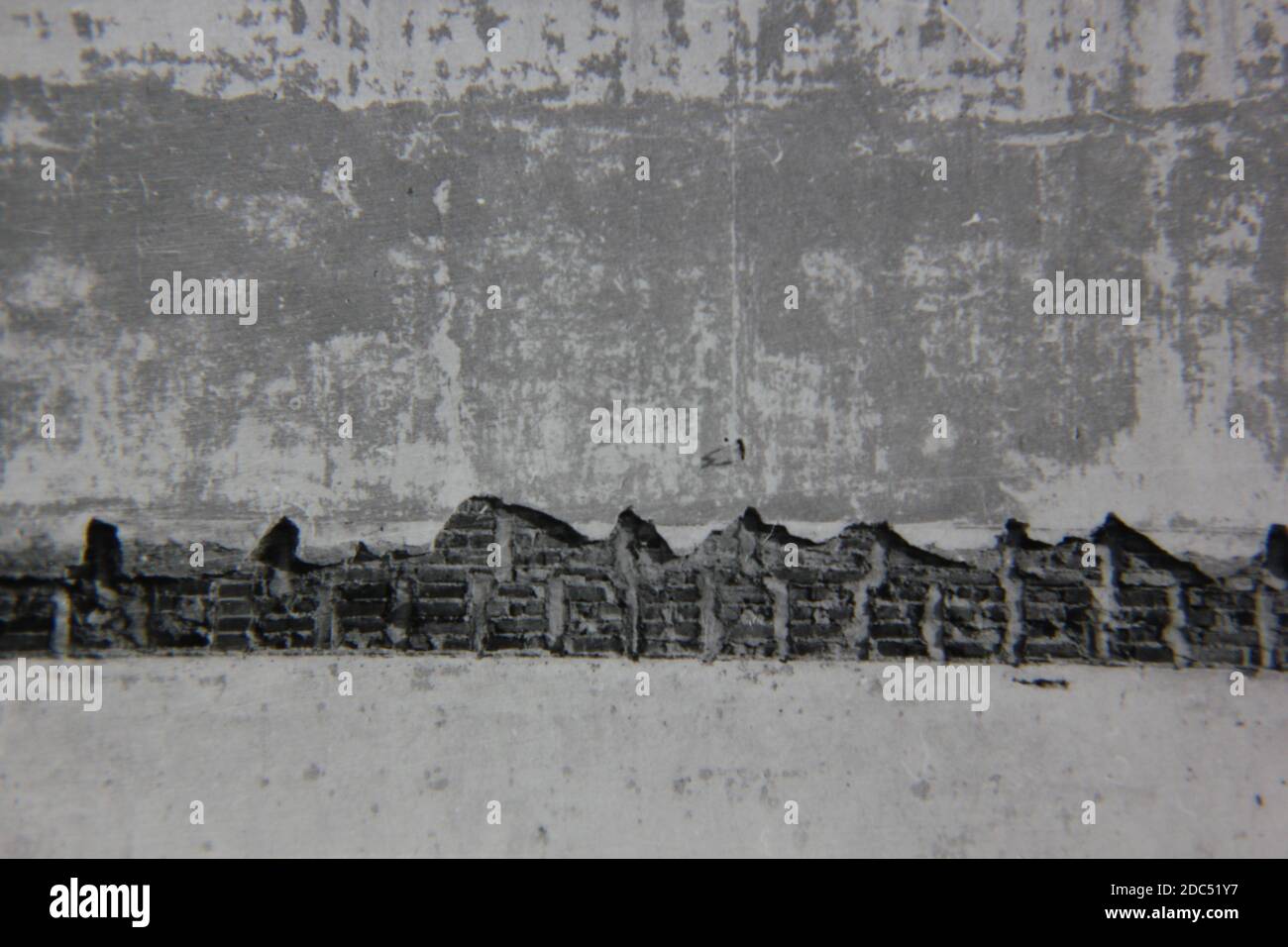 Belle photographie en noir et blanc vintage des années 1970 d'un mur en plâtre qui s'effrite avec une structure en brique. Banque D'Images