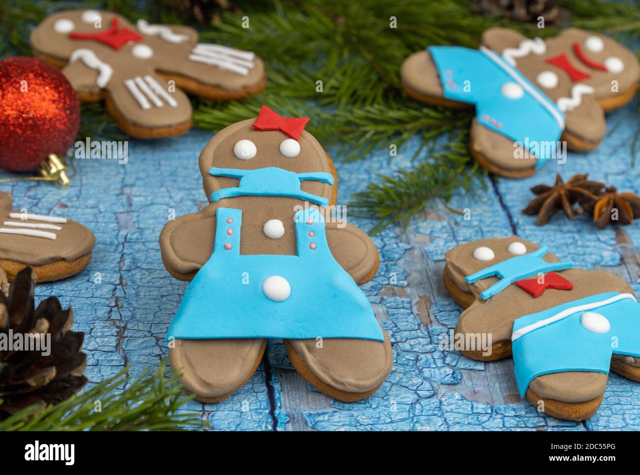 homme de pain d'épice dans un masque médical. Bandage respiratoire médical visage, masque de protection chirurgical. Biscuits faits à la main sur une surface en bois. Banque D'Images
